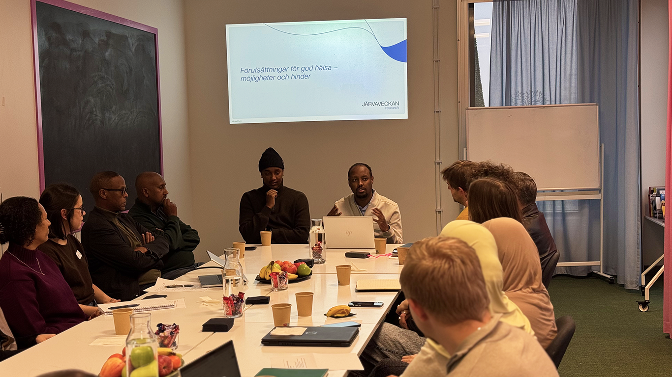 Människor sitter runt ett bord och har ett rundabordssamtal.